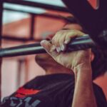 Focused shot of a man doing pull-ups in a gym, highlighting his strength and endurance.